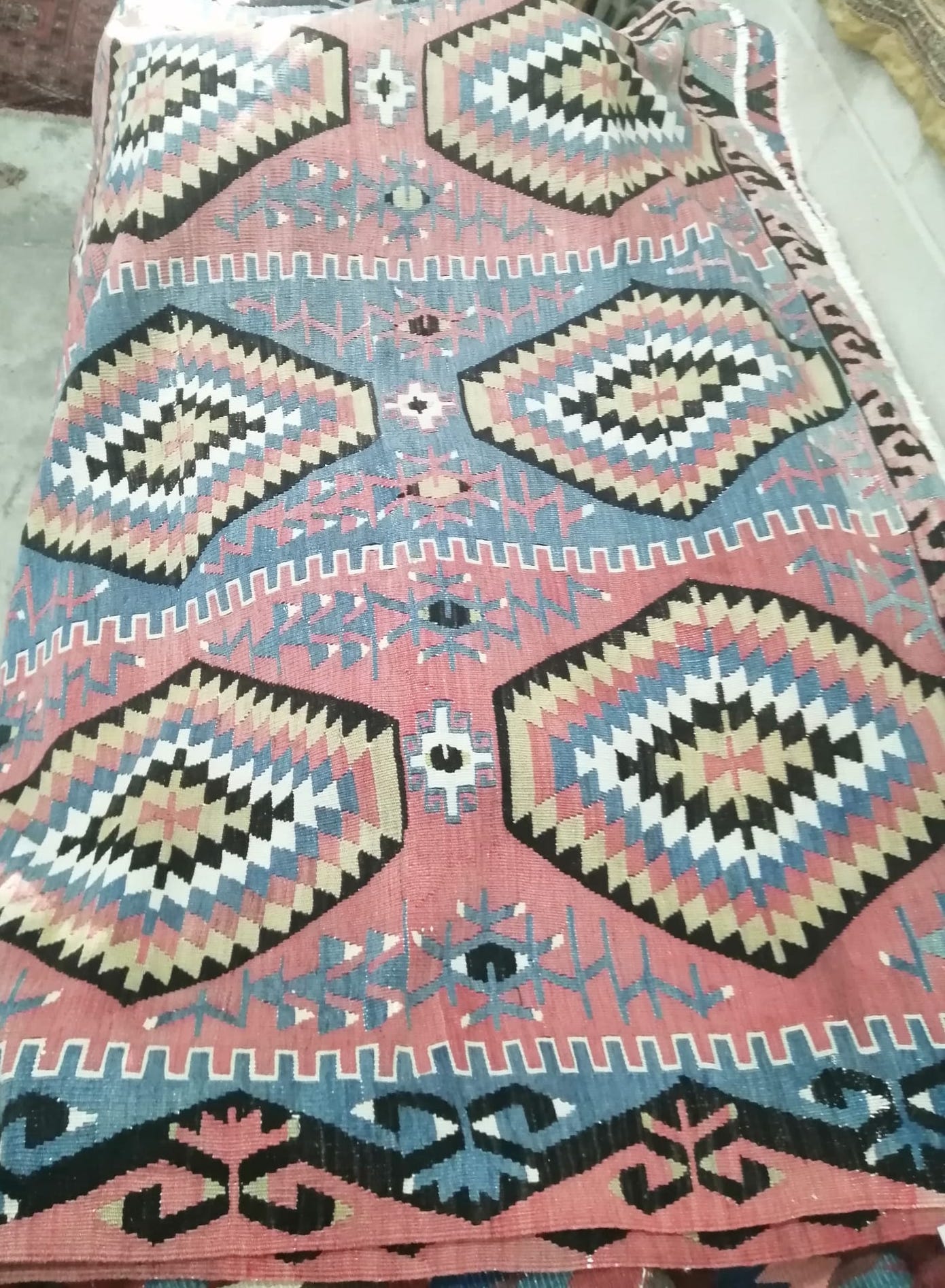 A pink ground flat weave Kilim rug woven with three rows of lozenges, approx. 240 x 160cm